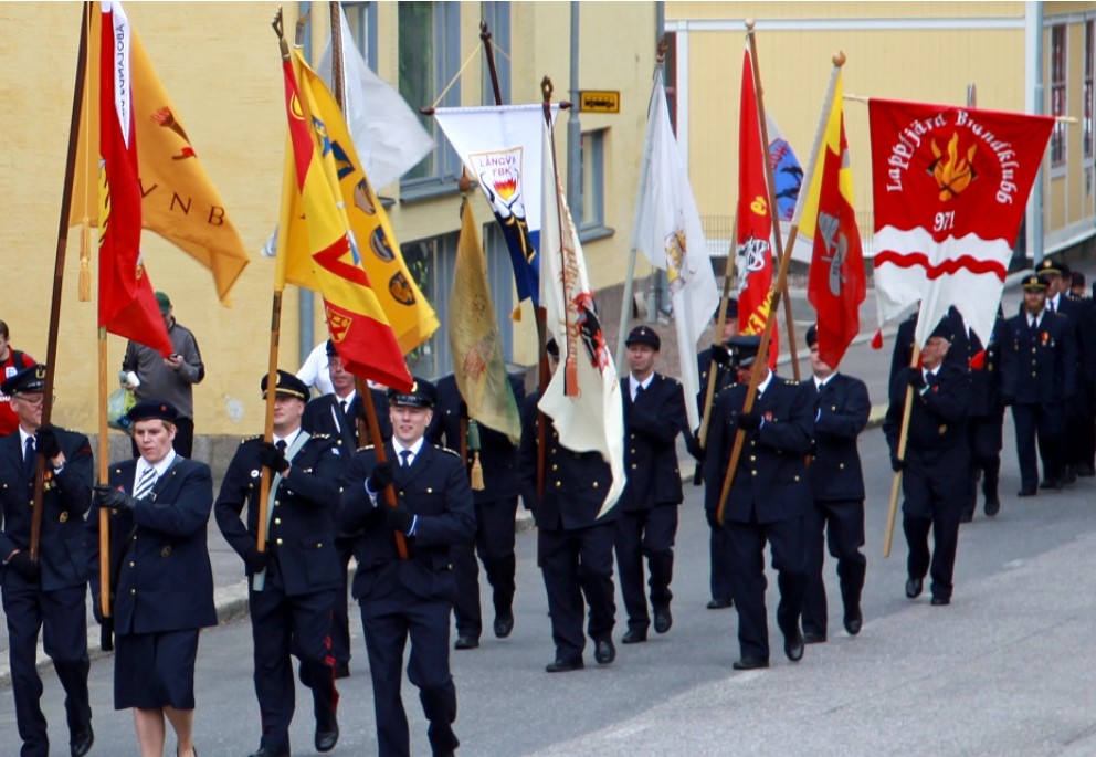 Avtalsbrandkårister marscherar med flaggor på gatan